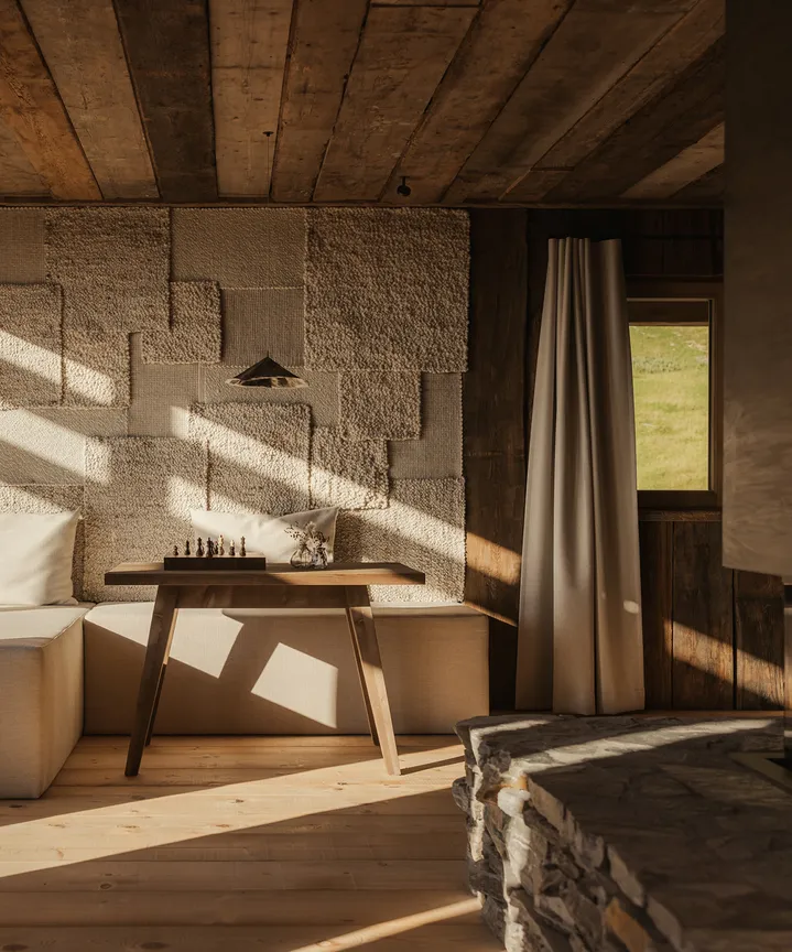 Handgefertigte Woll-Patchwork-Wand mit Schachspiel im sonnendurchfluteten Wohnbereich – alpine Handwerkskunst trifft Design im eriro Alpine Hide